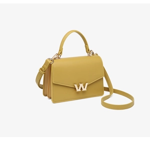 Detail of mustard yellow leather handbag showing the metallic W-shaped hardware lock