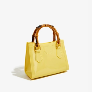 Detail view of the yellow jelly bag showing the vintage bamboo handle and gold D-ring