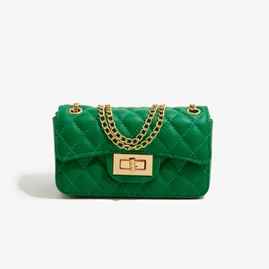 Close-up of green quilted leather texture and golden metal twist lock on mini flap bag