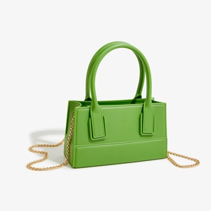 Detail view of the vibrant green PVC jelly bag with gold chain strap and stitching