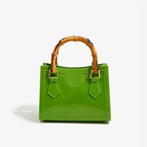Detailed macro of green glossy jelly bag with bamboo handle and gold metal hardware