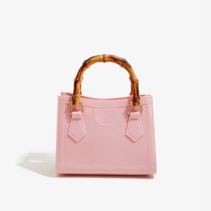 Detailed view of pink PVC jelly bag featuring retro bamboo handle and gold metal hardware