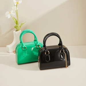 Détail de sacs gelée en PVC vert néon et noir avec chaînes dorées dans un décor moderne