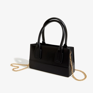 Detail of black PVC jelly bag with golden metal chain strap in a heart shape