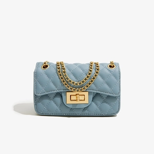 Close-up of the quilted texture and golden metal lock on the foggy blue crossbody bag