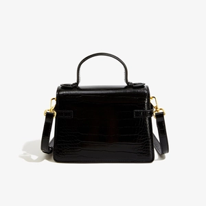 Détail du sac à main noir en similicuir crocodile avec texture brillante et boucles d'or