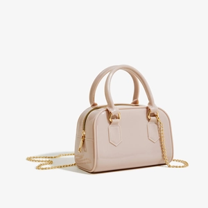 Détail macro du sac en PVC rose brillant montrant sa finition lisse et sa chaîne dorée