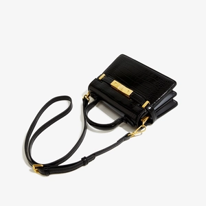 Détail de la texture crocodile noir et du fermoir doré sur le sac à bandoulière femme