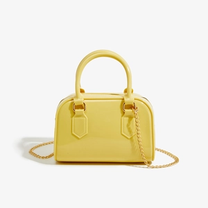 Détail du sac gelée en PVC jaune avec finition brillante et bandoulière chaîne dorée