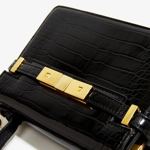 Détail du sac à main en cuir crocodile noir avec un élégant fermoir en métal doré
