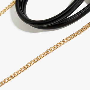 Detail of elegant gold metal chain link paired with soft black leather handle texture