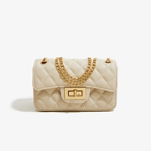 Close-up of quilted cream faux leather bag with gold chain strap and metal clasp