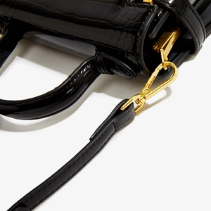 Détail de la texture cuir de crocodile noir avec des finitions métalliques dorées chic