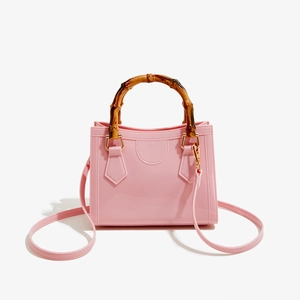 Detailed macro view of the natural bamboo handle and shiny pink PVC jelly handbag texture