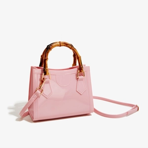 Close-up of pink glossy PVC jelly bag featuring a vintage bamboo handle and gold hardware