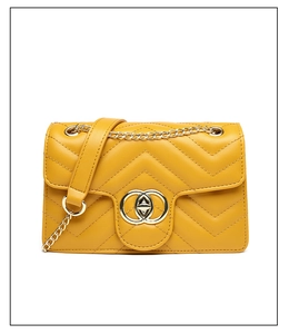 Detail of yellow chevron quilted handbag with gold interlocking buckle and chain strap