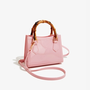 Detail of pink jelly bag showing bamboo handle and gold hardware on PVC finish