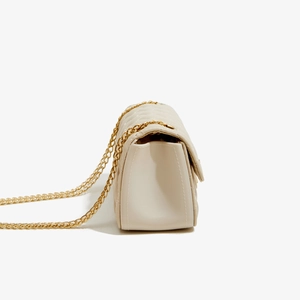 Detail view of beige quilted PU leather crossbody bag with golden chain strap
