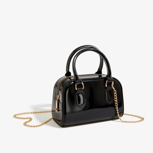 Vue détaillée du sac en cuir verni noir avec chaîne dorée et finition brillante