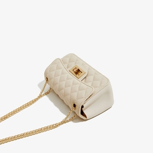 Detail of cream quilted PU leather bag with gold metal twist lock and chain strap