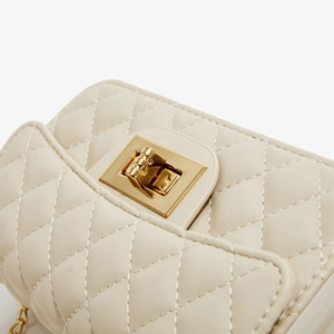 Close-up of cream PU leather shoulder bag with quilted diamond pattern and gold metal clasp
