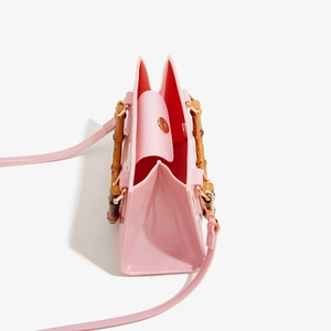 Detailed side view of pink PVC jelly bag with bamboo handle and accordion fold side