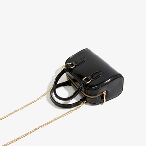 Détails du sac Boston en cuir verni noir avec sa bandoulière en chaîne dorée chic