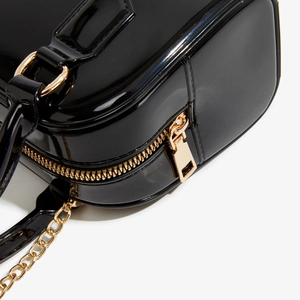 Détail de la fermeture éclair dorée et de la chaîne sur sac en PVC noir brillant