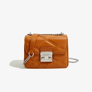 Détail de la texture en cuir PU matelassé marron caramel avec boucle métallique sur sac carré