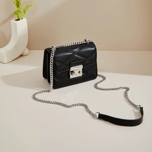 Détail du sac bandoulière matelassé noir avec boucle argentée et bandoulière en chaîne