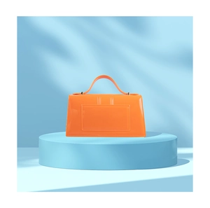 Vue détaillée du sac en PVC orange brillant sur un socle bleu avec des ombres