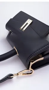 Close-up of black crossbody bag showing fine leather texture and golden metal buckle details
