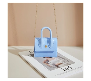 Detail of light blue PVC jelly bag with gold chain strap and metallic snap button closure