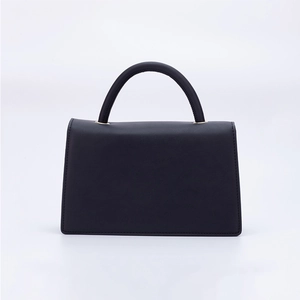 Minimalist black matte leather trapezoid handbag with top handle and magnetic flap closure