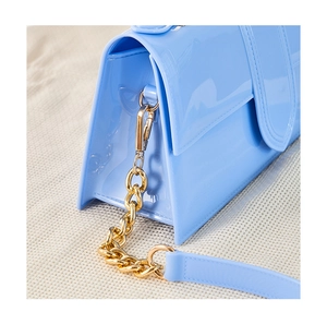 Gros plan d'un sac gelée bleu clair montrant la texture PVC brillante et chaîne dorée