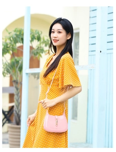 Outdoor shot of a pink PVC crescent hobo bag featuring a gold piston lock closure