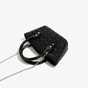 Detail der schwarzen PVC-Flechtasche mit glänzendem Finish und silberner Metallkette
