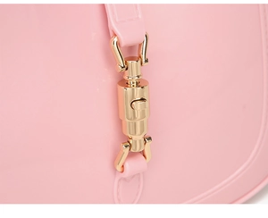 Close-up of pink crescent jelly bag featuring a golden metallic piston closure clasp