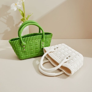 Detail der Webstruktur und Silbernieten an grünen und beigen PVC-Korb-Handtaschen