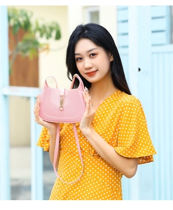 Detailed view of the pink PVC crescent bag featuring a golden metal lock on a floral dress