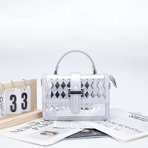 Detail of silver geometric quilted small shoulder bag with metallic lock and flap closure