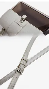Detail of silver-grey cross-pattern flap with branded metallic buckle and adjustable strap