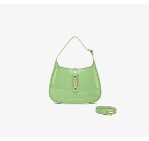 Detail view of light green PVC crescent bag featuring gold piston lock and polished finish
