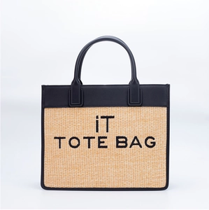 Close-up of the black leather handles and woven straw material on the iT TOTE BAG
