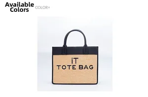 Detail view of woven straw and black leather tote bag with embroidered iT TOTE BAG text