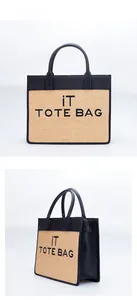 Detail view of straw woven tote bag with black leather trim and iT TOTE BAG embroidery
