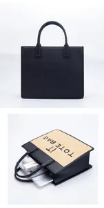 Detail view of large straw tote with 'IT TOTE BAG' text and sleek black faux leather handbag