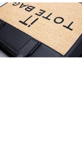Close-up detail of woven straw texture and IT TOTE BAG embroidery on black leather trim