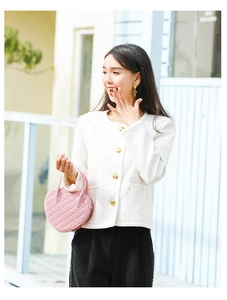Close-up of a pink heart-shaped quilted jelly bag held by a model in a tweed jacket