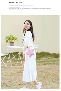 Détail du sac bandoulière rose en forme d'étoile avec une robe vintage blanche